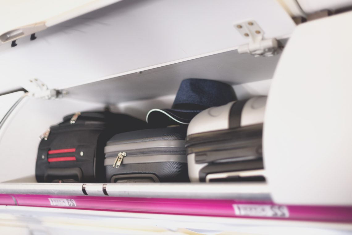 Hand luggage compartment with suitcases in airplane. Carry on luggage on top shelf of plane. Travel concept with copy space Hand luggage compartment with suitcases in airplane. Carry on luggage on top shelf of plane. Travel concept with copy space