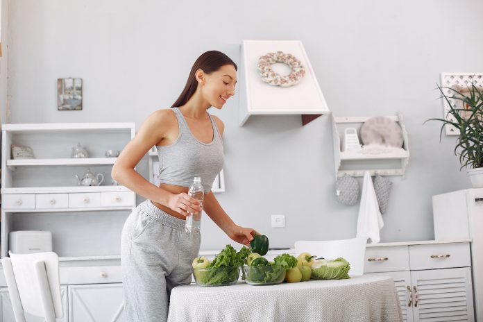 Beautiful and sporty girl in a kitchen with a vegetables